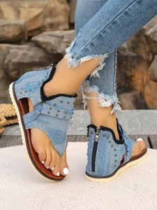 Detailed view of blue denim thong sandals featuring metal studs and a back zipper design