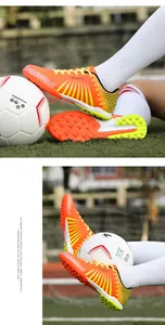 Detail of vibrant orange TF soccer cleats showing outsole and side design with ball