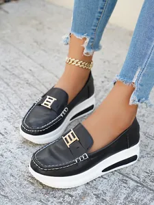 Close-up of black PU platform loafers with gold H-buckle and white stitching details