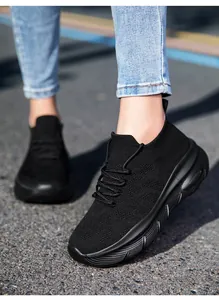 Close-up of black breathable knit sock sneakers with chunky non-slip sole on feet outdoors
