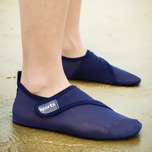 Close-up detail of breathable blue mesh water shoes being worn on a sunny sandy beach