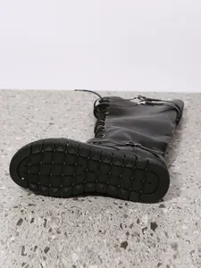 Detailed view of non-slip sole and strap buckles on black PU tall boots