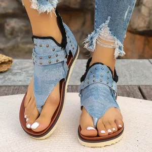 Detail view of stylish denim thong flat sandals with bronze studs and a rear zipper
