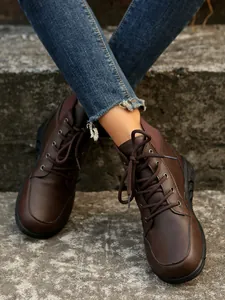 Detailed view of women's vintage brown lace-up ankle boots worn on stone steps.