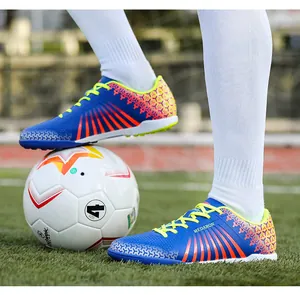 Professional blue and orange soccer cleats shown on grass field with a football.