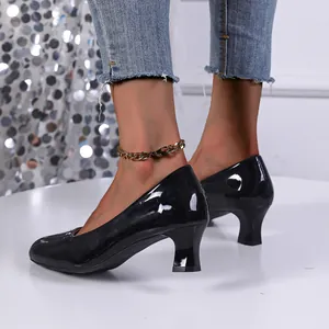 Side view detail of black patent leather pumps with chunky heels and gold anklet
