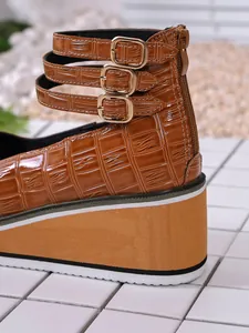 Zoom sur talon compensé en cuir verni marron croco avec triple bride à boucle