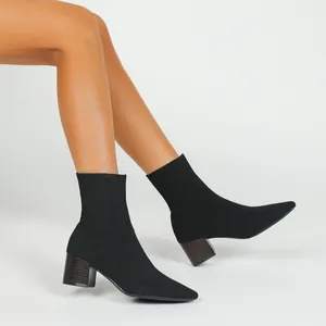 Detailansicht schwarzer spitzer Strick-Sockenstiefel mit klobigem Absatz in Holzoptik.