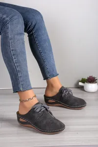 Detailed macro view of dark grey lace-up wedge mules with hollow-out laser-cut patterns