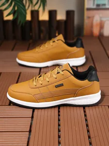 Vista lateral de zapatillas marrones impermeables para hombre sobre suelo de madera.