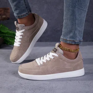 Détail de baskets en daim kaki avec lacets blancs et semelles en caoutchouc blanc