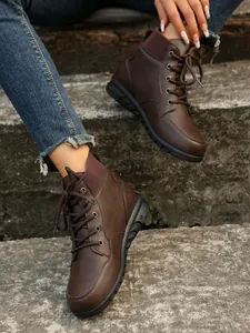 Macro detail of brown British style lace-up ankle boots for women on stone steps
