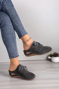 Close-up of women's grey lace-up wedge mules featuring elegant floral hollow cutouts.