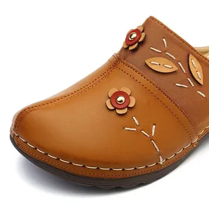 Detailed view of brown leather wedge slide sandal featuring floral decor and stitching.