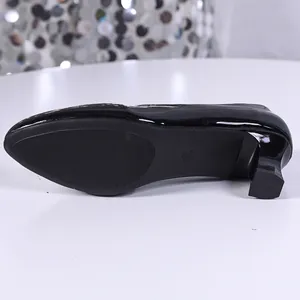 Close-up view of the sole and block heel of black patent leather pointed toe pumps