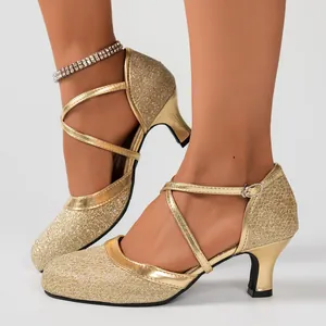 Nahaufnahme eleganter goldener Glitzer-Sandaletten mit schicken Kreuzriemen am Knöchel.