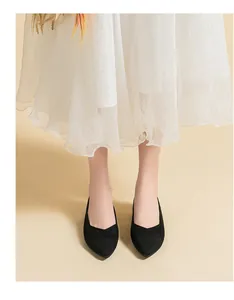 Close-up of black breathable knit pointed-toe flats styled with a white midi skirt.