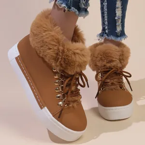 Close-up of brown faux leather snow boots with thick tan faux fur trim and white platform