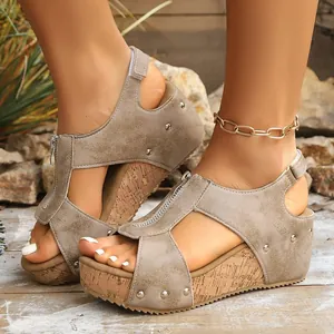 Close-up of women's taupe wedge sandals with cork heel and metal stud details