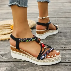 Detail view of bohemian wedge sandals with braided straps and rhinestones on boardwalk