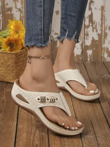Detail showing the white wedge flip-flops with perforated design and gold buckles