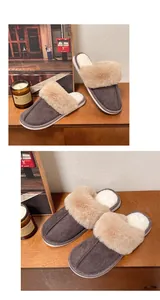Close-up of cozy grey suede slippers with thick beige faux fur trim on a wooden shelf.
