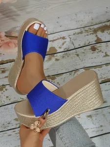 Gros plan sur la bride en tissu bleu et la plateforme dorée de ces sandales compensées