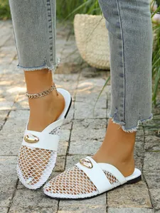 Detailed view of white breathable mesh flat mules with a metallic gold buckle accent