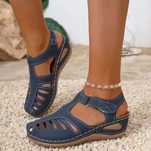 Detailed view of blue retro Roman sandals with wedge heel and decorative white contrast stitching.