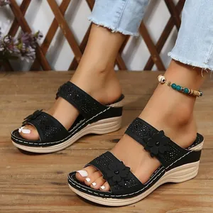 Women's black wedge sandals with flower accents and decorative stitching.
