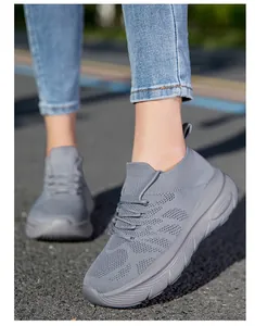 Detail view of grey flyknit sock sneakers with thick soles worn by a model outdoors