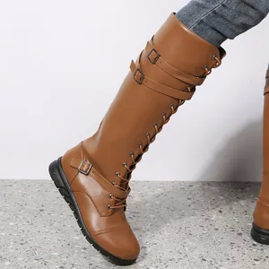 Close-up of brown PU leather knee-high boots with multi-buckle straps and lace-up detail