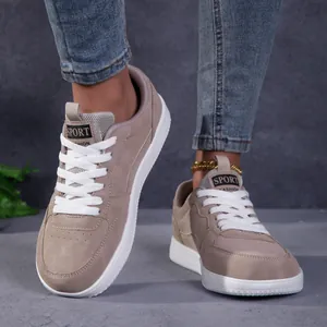 Détail de baskets en daim taupe avec lacets blancs dans un décor de rue urbain
