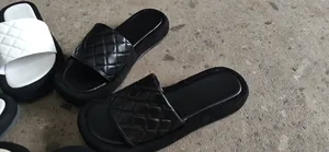 Λεπτομερής προβολή των καπιτονέ μαύρων και λευκών σανδαλιών πλατφόρμας με μοτίβο ρόμβου