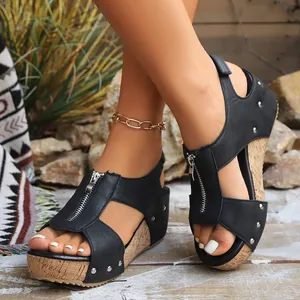 Close-up detail view of black wedge sandals with front zipper and cork platform sole.