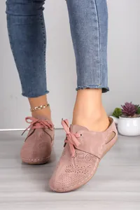 Detailed view of pink perforated leather lace-up mules on a model's feet