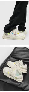Detailed view of white streetwear sneakers with braided rope laces and frayed edges