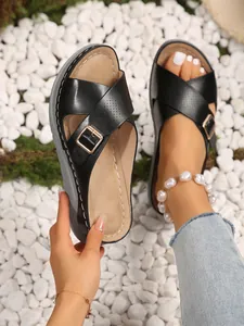 Detailed view of women's black cross-strap platform sandals with a gold buckle.