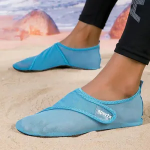 Durable blue mesh aqua shoes for beach and swimming, worn on sandy beach terrain