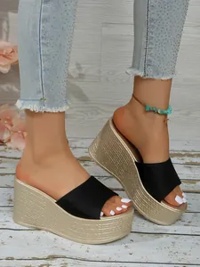 Vue détaillée de sandales compensées noires et dorées portées avec un jean en denim