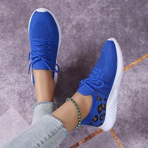 Detail shot of blue knit sneakers with leopard print heel and white textured sole.