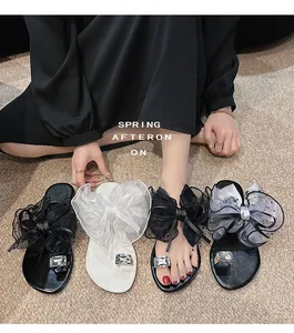 Detailansicht eleganter flacher Sandalen im Feen-Stil mit großen Schleifen und Kristallen.
