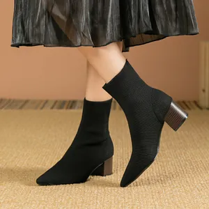 Detailansicht der schwarzen spitz zulaufenden Strick-Stiefeletten mit braunem Blockabsatz.