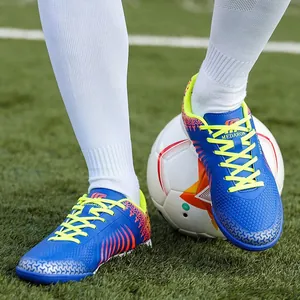 Blue synthetic soccer shoes with yellow laces for men and youth on a grass football pitch