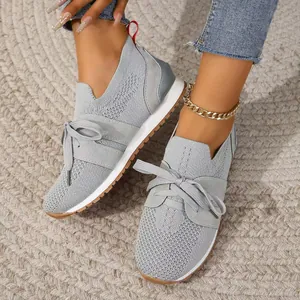 Stylische graue Damen-Sneaker aus Fly-Knit, kombiniert mit Jeans und einem Fußkettchen