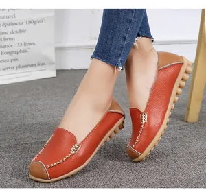 Close-up detail of women's orange leather loafers with contrast stitching.