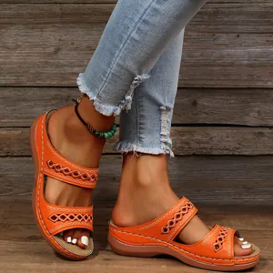 Sandales compensées orange stylées avec motifs ajourés portées par un mannequin chic