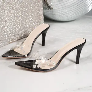 Detailed view of elegant transparent pointed toe high heel mules with pearl accents.