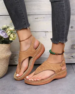 Detailansicht von braunen bestickten Zehentrenner-Sandalen an einem Modell getragen