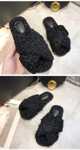 Nahaufnahme gemütlicher schwarzer flauschiger Teddy-Fleece-Hausschuhe mit Überkreuz-Design